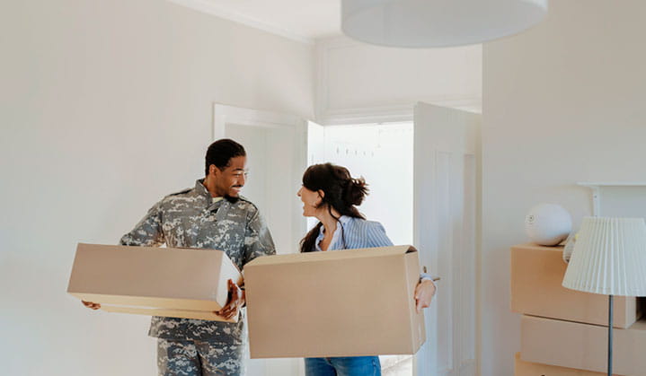 Veterano militar y su pareja llevando cajas a su nueva vivienda con el préstamo hipotecario para militares de BOK.